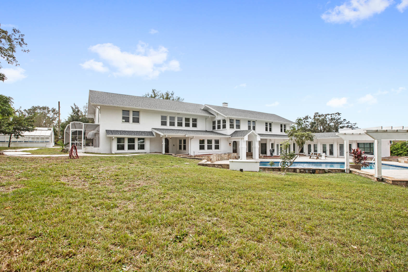 back of estate home with white paint and pool